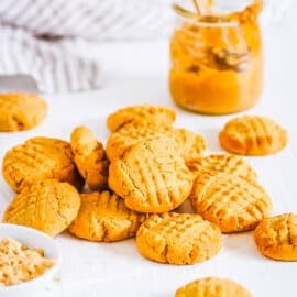 Powdered peanut butter cookies stacked on a sheet of parchment paper.