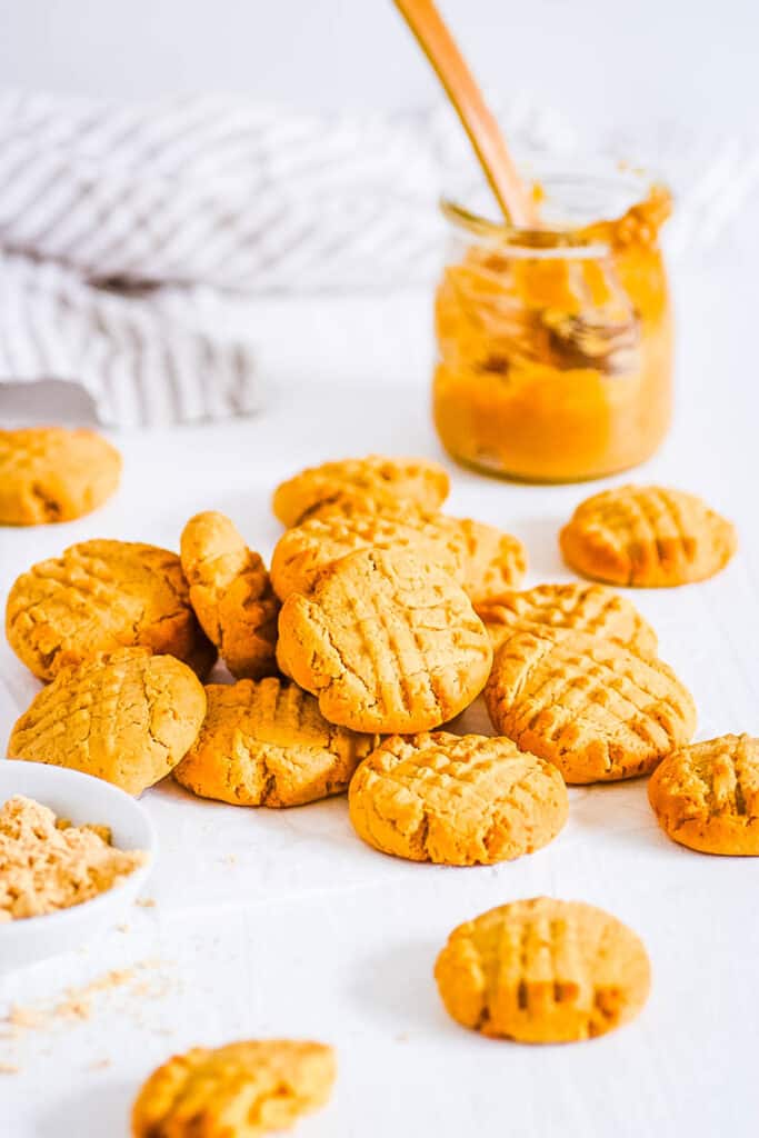 Powdered peanut butter cookies stacked on a sheet of parchment paper.