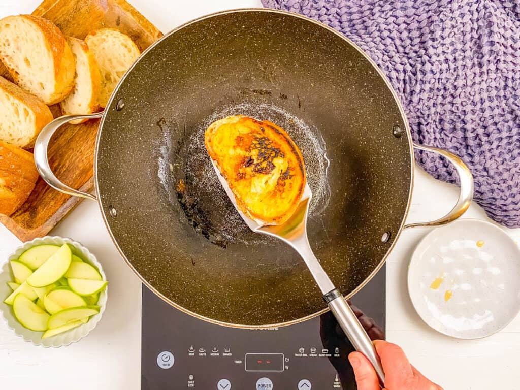 Sourdough grilled cheese sandwich with apple and brie being grilled in a pan.