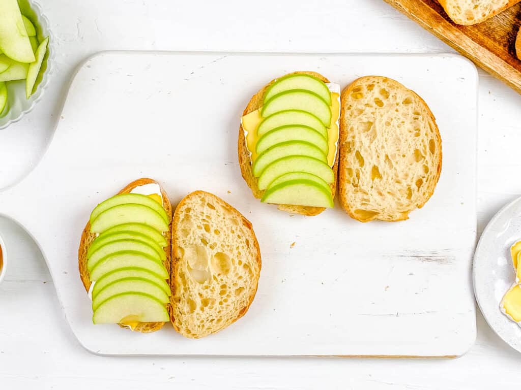 Apple slices stacked on top of sourdough bread slices for sourdough melt sandwiches.