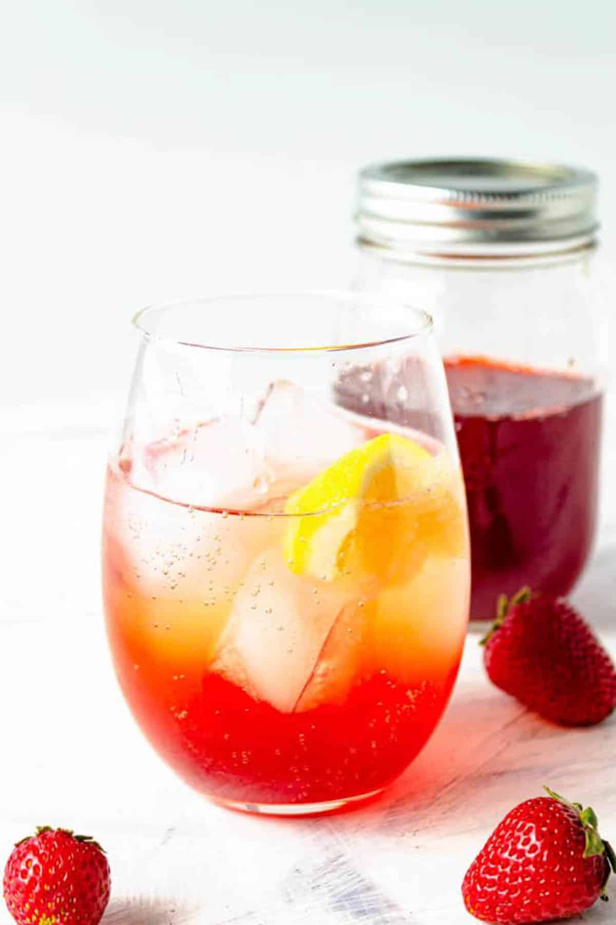Cocktail met ijs met eenvoudige aardbeiensiroop, gegarneerd met een citroen.