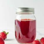 Homemade easy strawberry simple syrup for drinks stored in a mason jar.