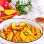Vegan roasted potatoes with rosemary in a white bowl.