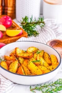 Vegan roasted potatoes with rosemary in a white bowl.