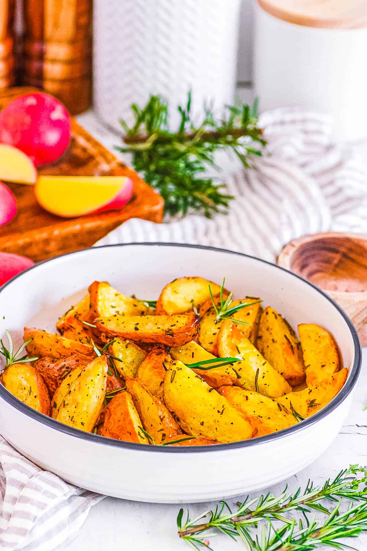 Vegan roasted potatoes with rosemary in a white bowl.