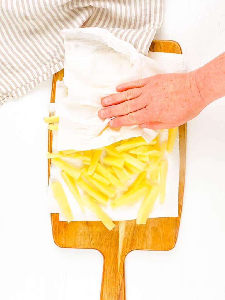 C،ava sticks being patted dry with paper towels on a cutting board.