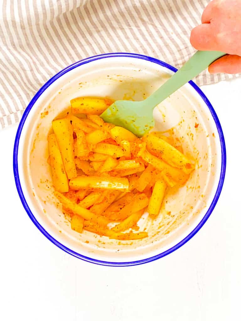 Yuca root fries tossed with spices and olive oil in a bowl.