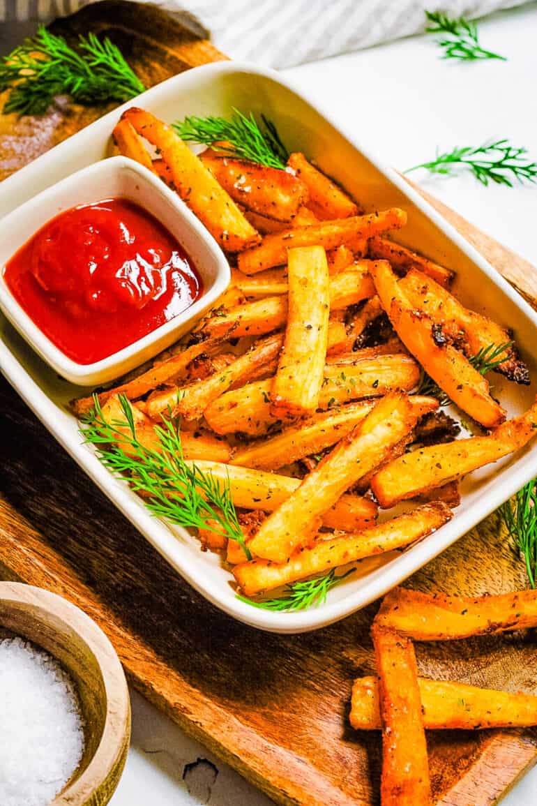 Air fryer yuca fries served in a white serving dish with ketchup.
