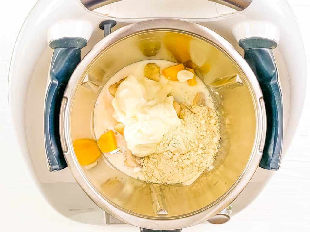 Mangoes, protein powder, bananas and milk added to a food processor.