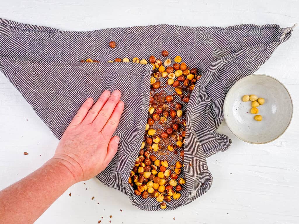 Roasted hazelnuts rubbed in between kitchen towels to remove the skin.