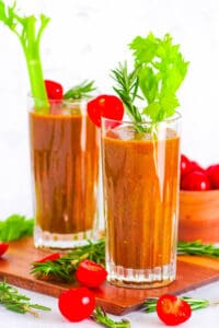 Healthy tomato smoothie in a glass garnished with celery and cherry tomatoes.