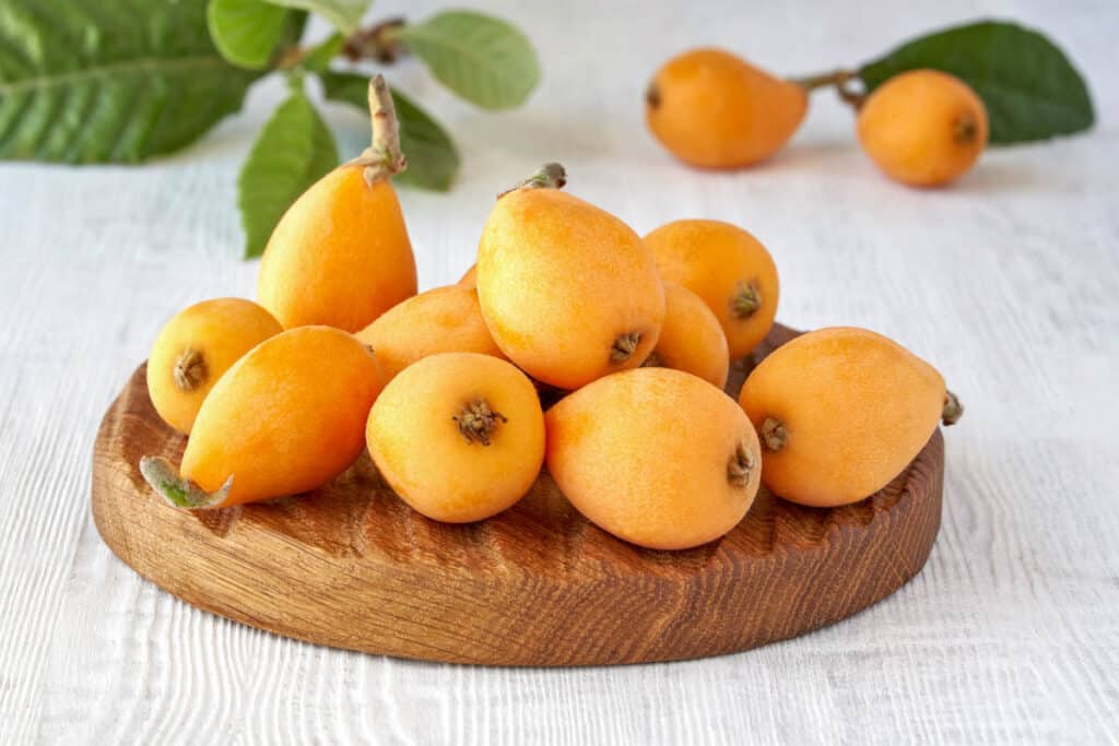 Japanese plums on a wooden cutting board.