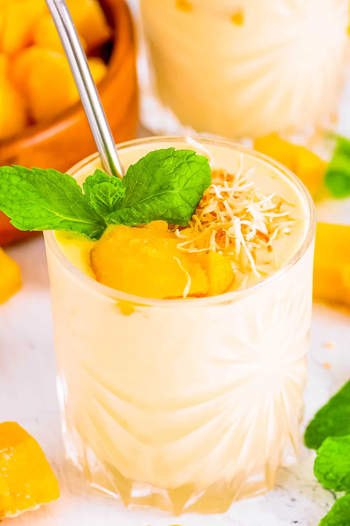 High protein mango smoothie served in a glass, garnished with mango chunks and mint.