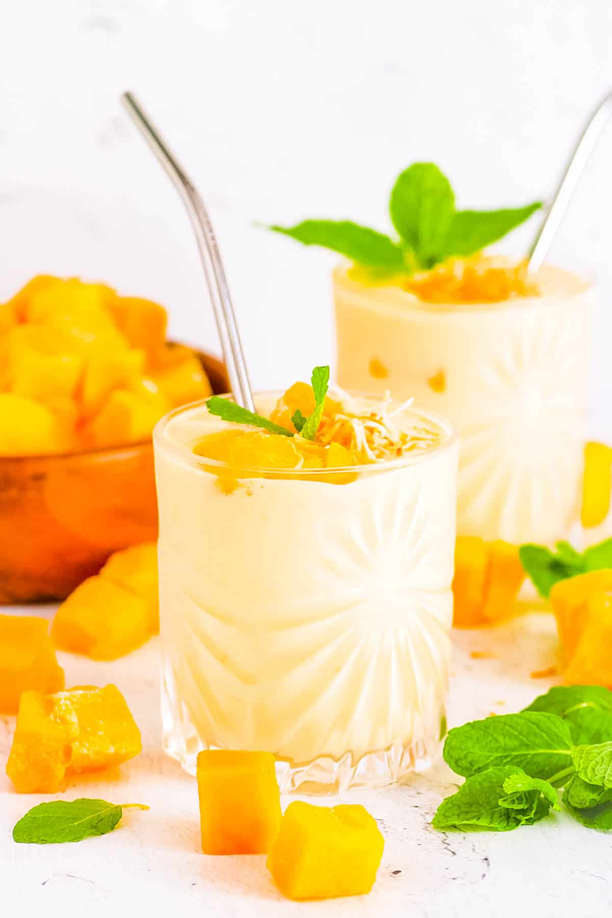 Healthy mango protein smoothie served in a glass, garnished with mango chunks and mint.