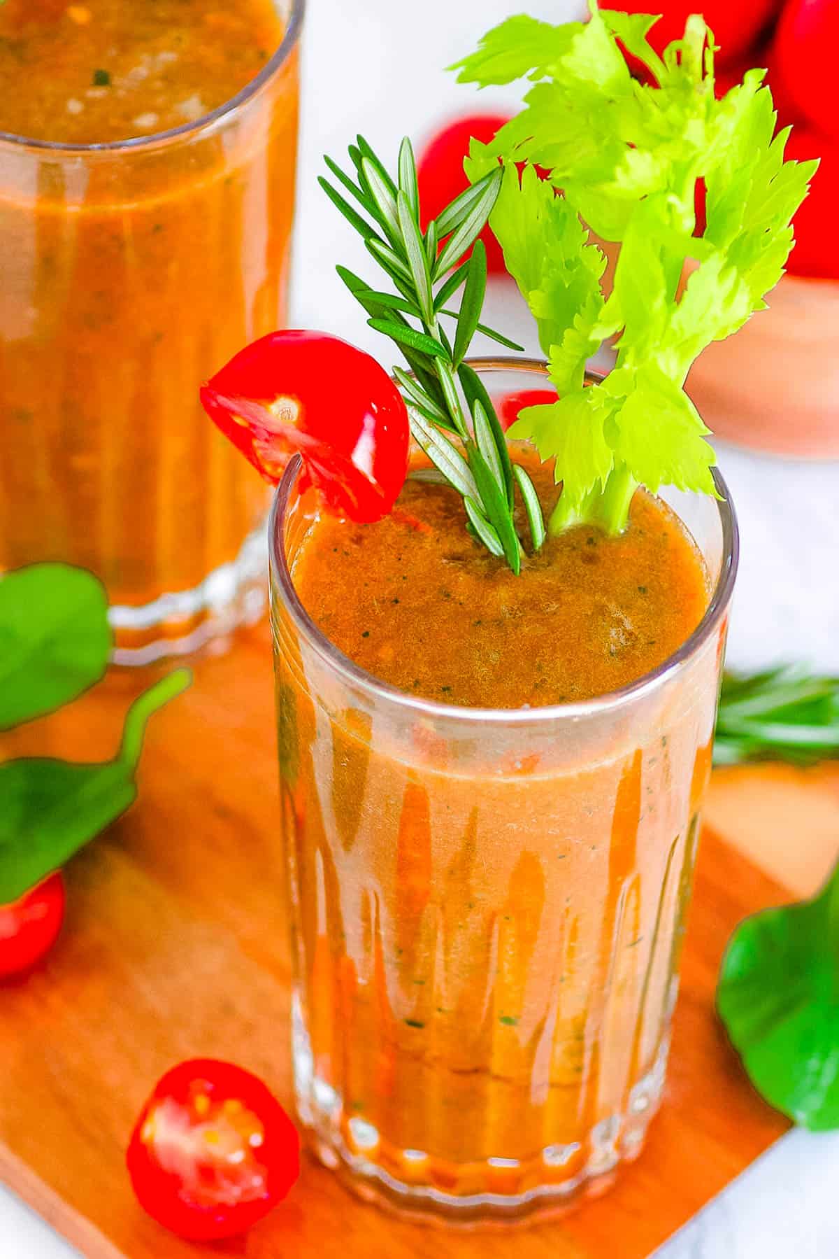 Savory tomato smoothie in a glass garnished with celery and cherry tomatoes.