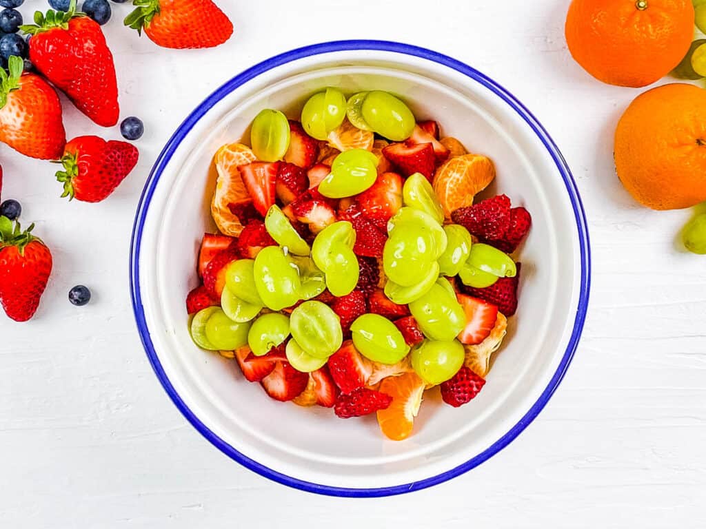 Grapes, oranges and strawberries mixed in a mixing bowl.