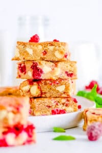 White chocolate and raspberry blondies stacked on a white plate.