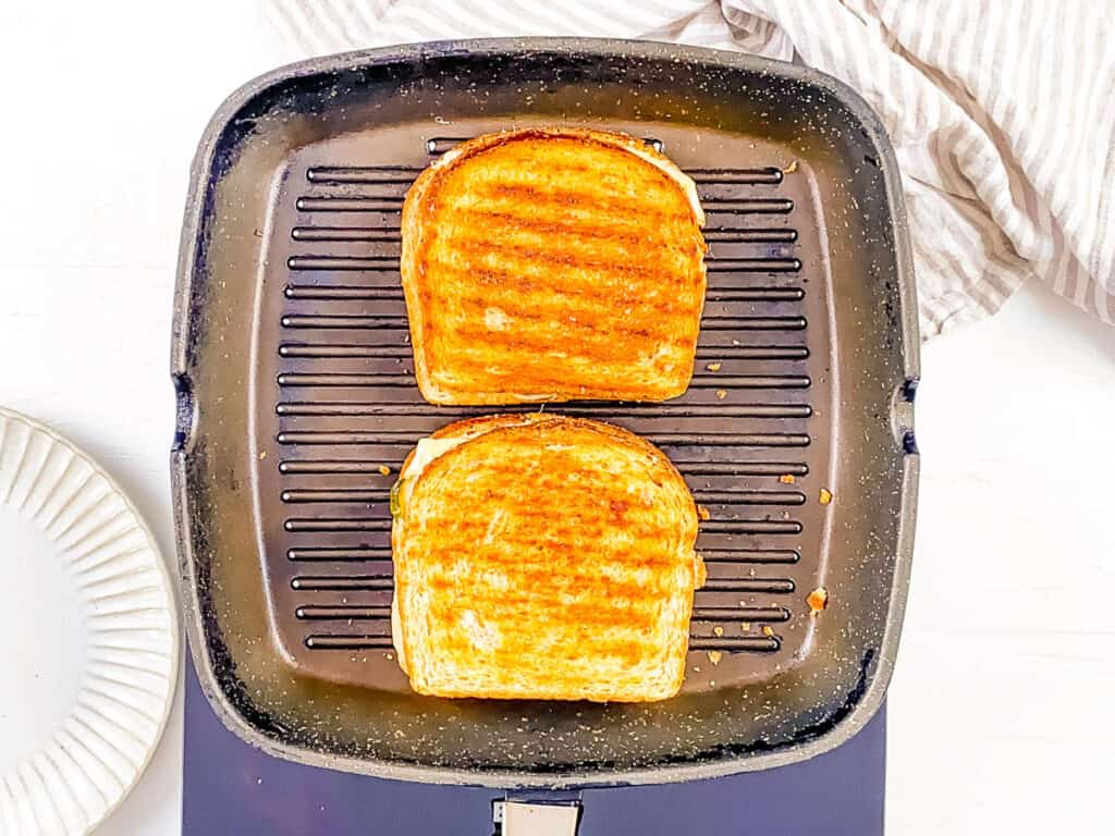 Cheese and pickle toastie cooking on a grill pan.