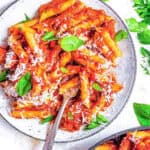 Red lentil pasta served on a white plate with homemade marinara sauce.