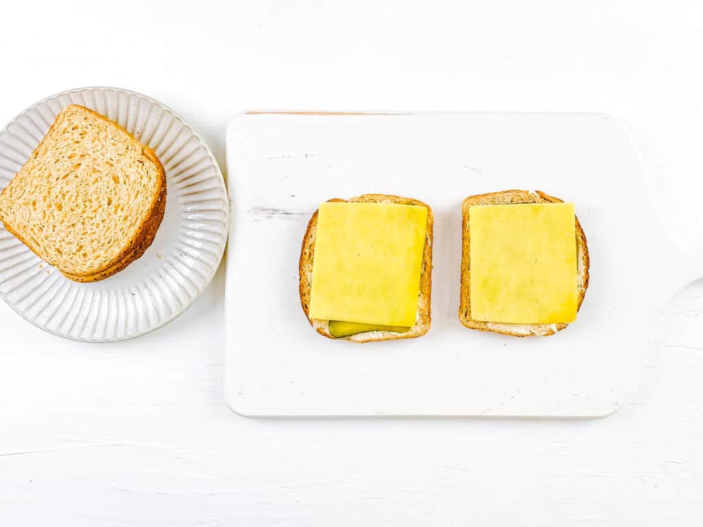 Cheese added to slices of bread with pickles and mayo.