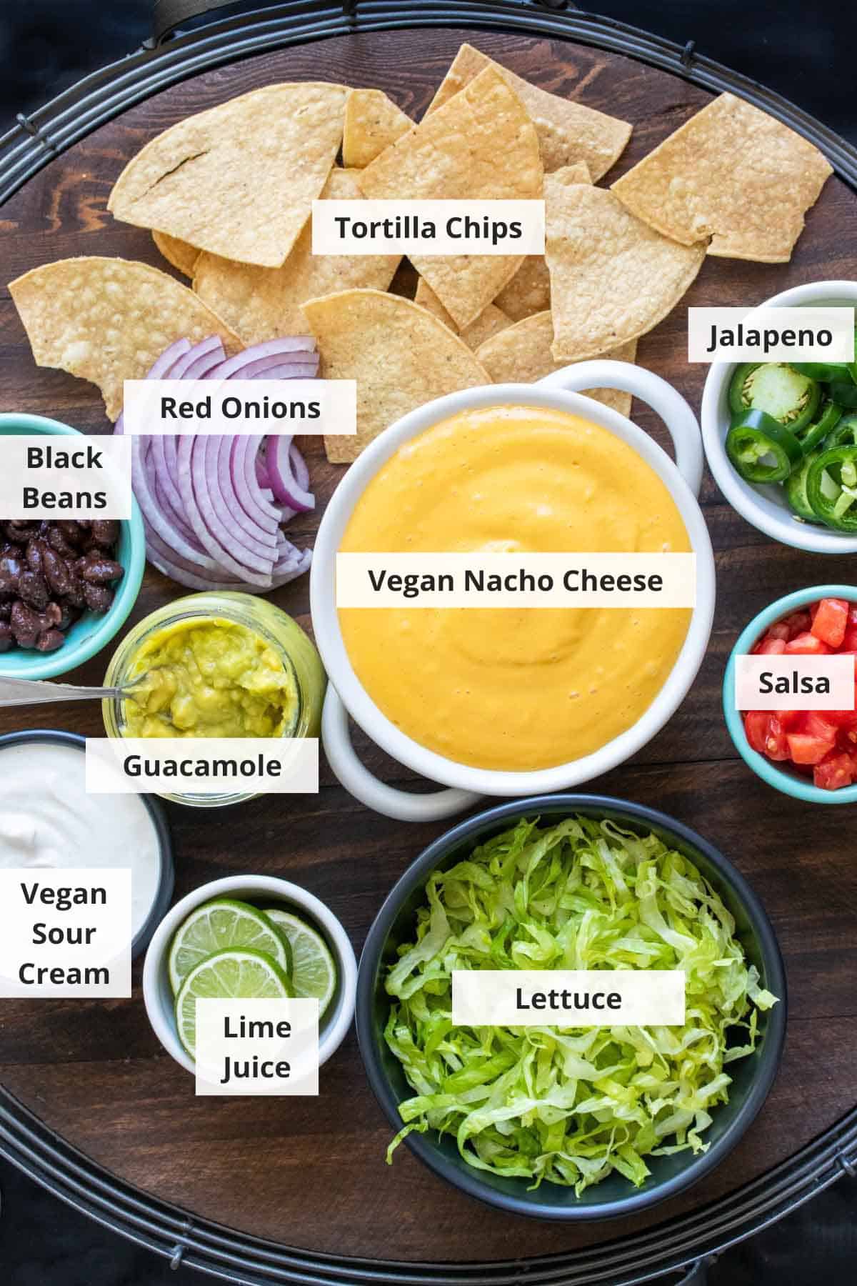 Ingredients for loaded vegan nachos on a wood background.