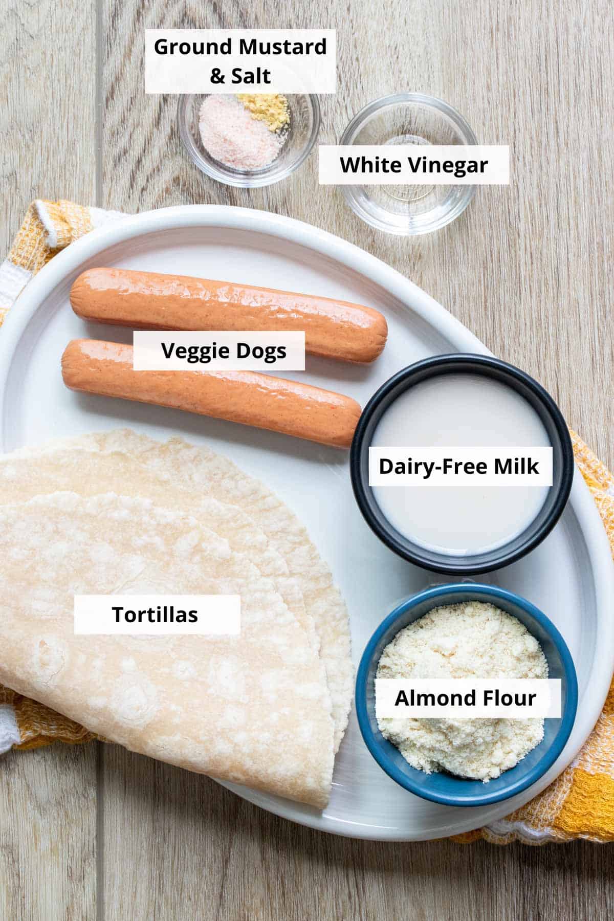 Ingredients for vegan pigs in a blanket recipe on a wood background.