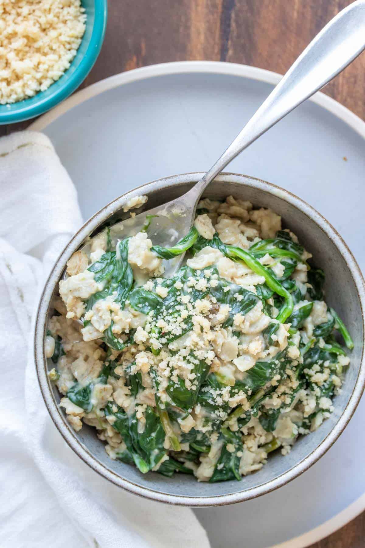 Spoon in a bowl filled with spinach oatmeal on a grey plate