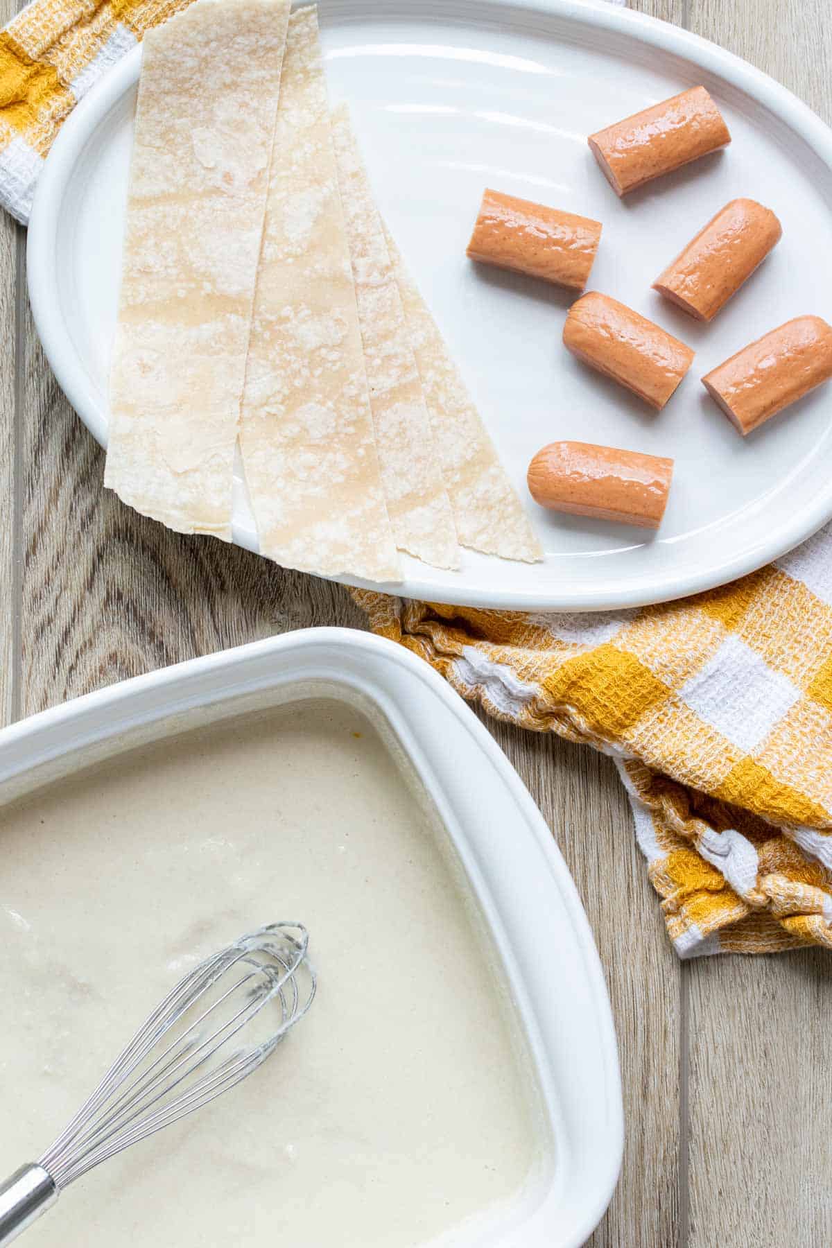 Cut up hot dogs and tortilla strips on a plate next to batter.