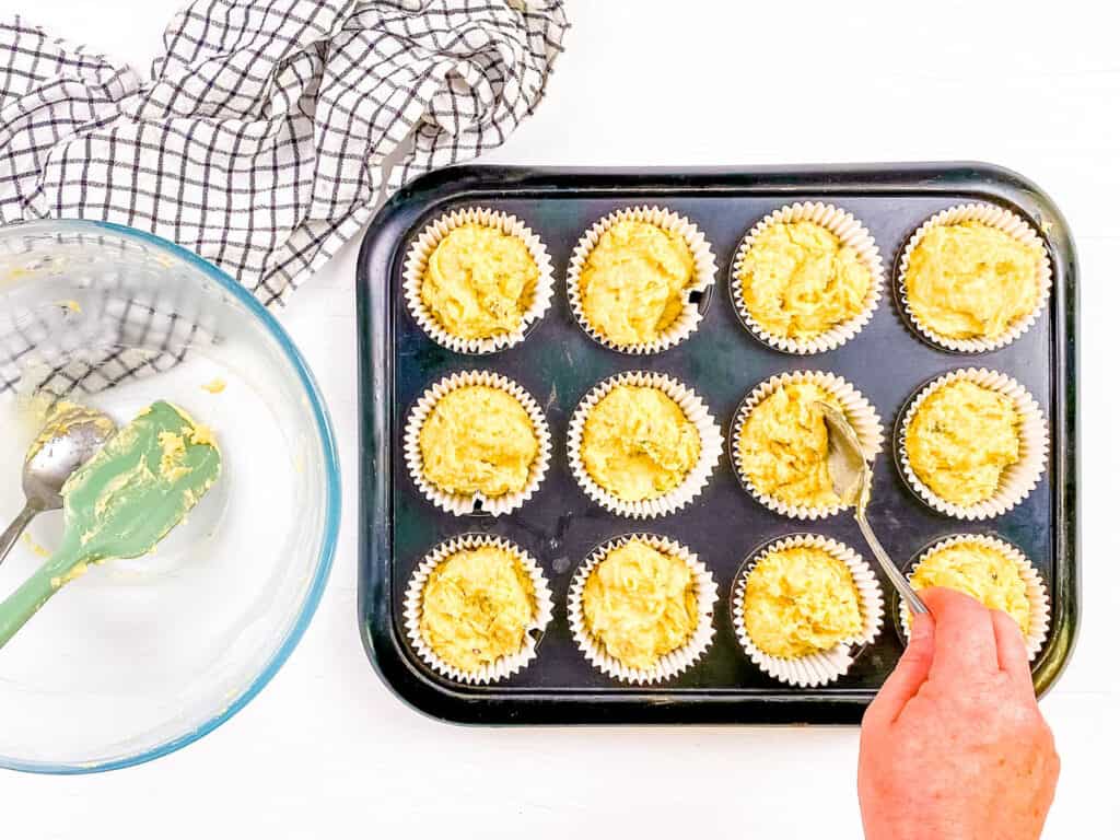 Muffin batter being added to muffin tins.