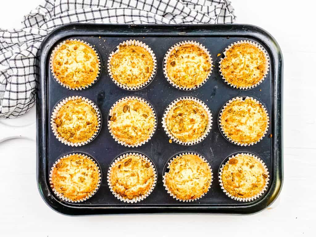 Bakery style pistachio muffins in a muffin tin, fresh out of the oven.