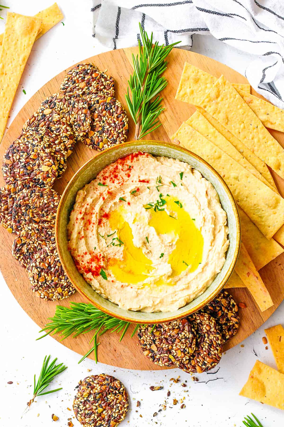 Butter bean hummus served in a bowl, with olive oil drizzled on top and crackers on the side.