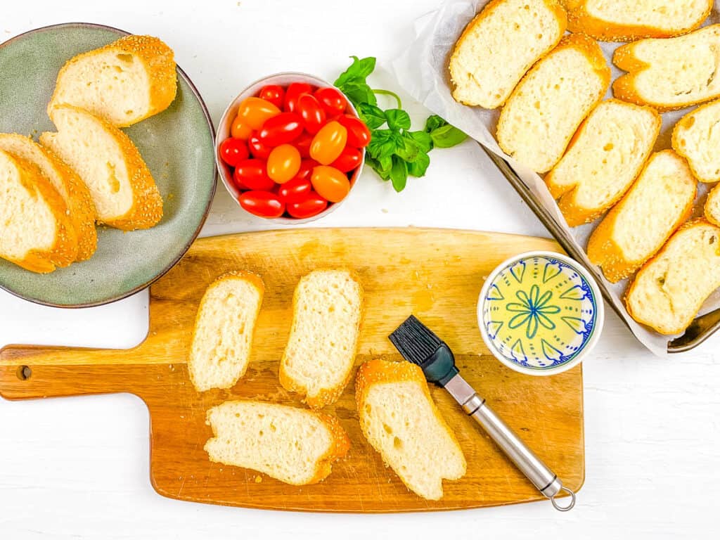 Bread slices brushed with olive oil on a cutting board.