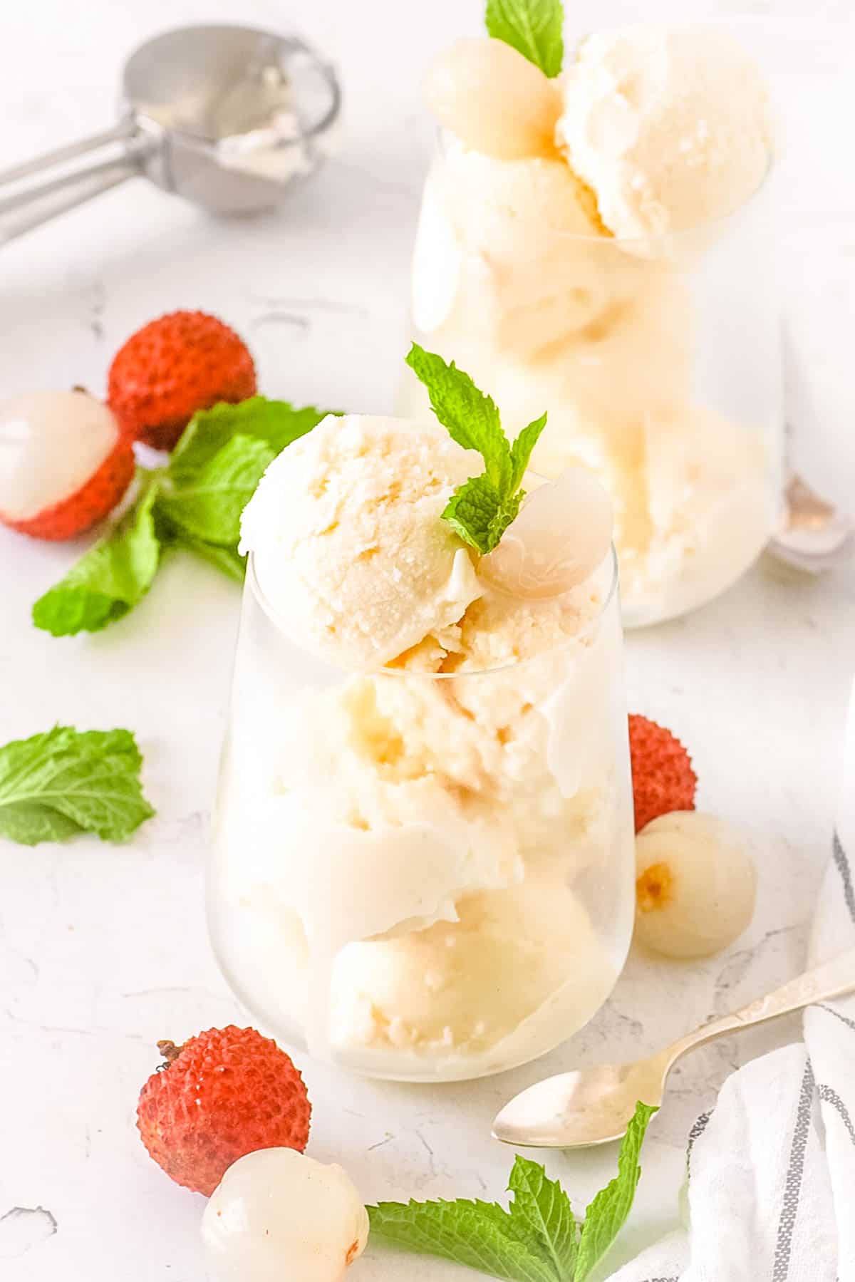 Creamy lychee ice cream served in a glass with mint garnish.