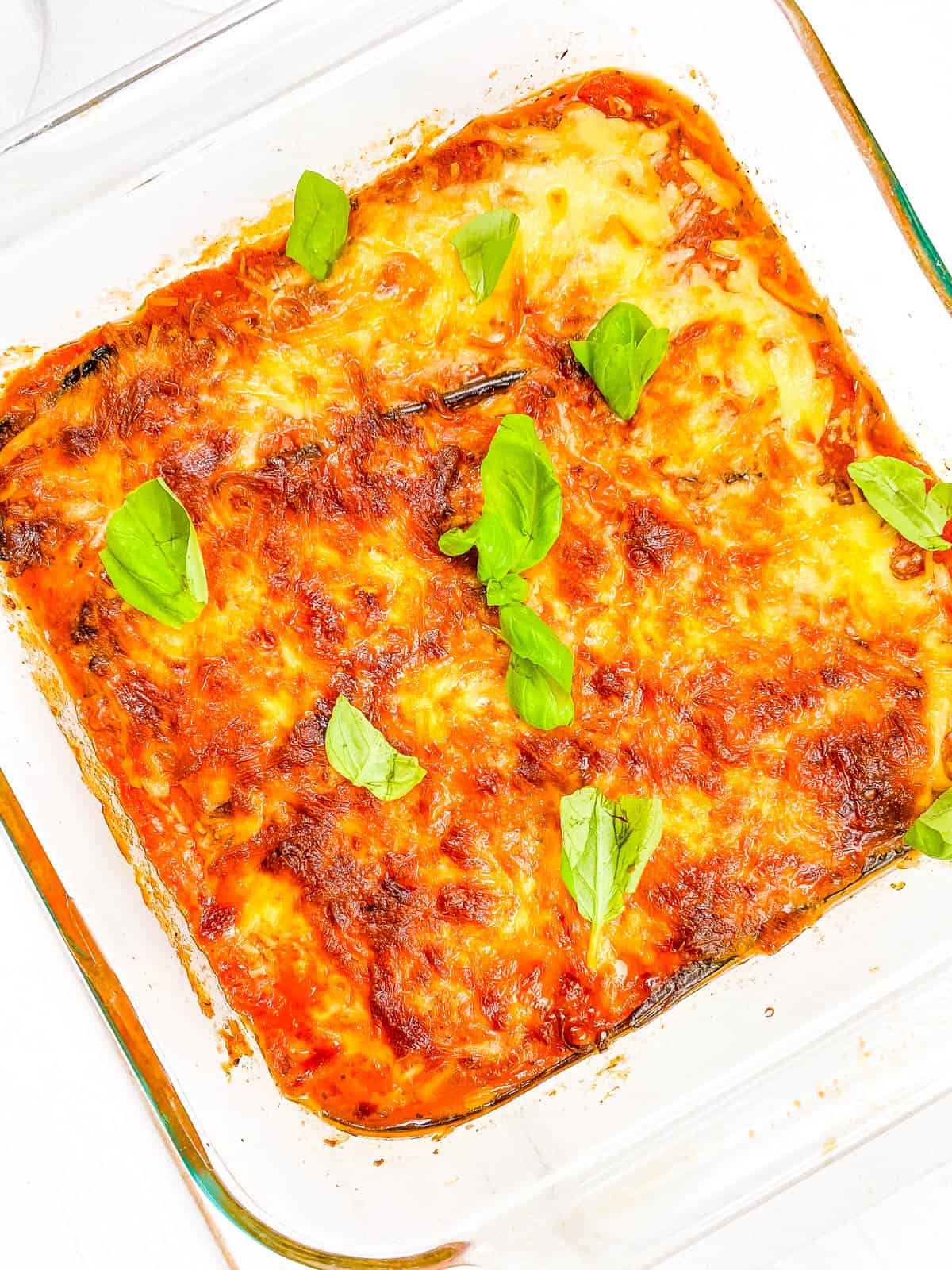 Vegan eggplant parmesan without breadcrumbs served in a baking dish garnished with fresh basil.