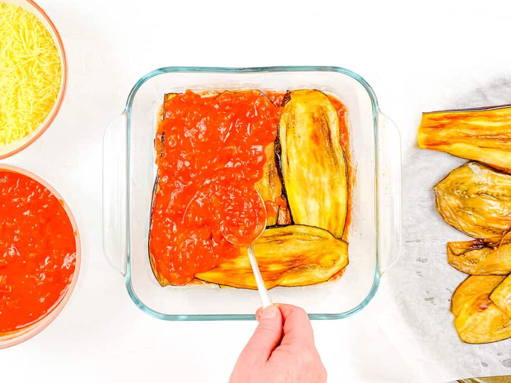 Eggplant slices and marinara sauce layered in a baking dish.