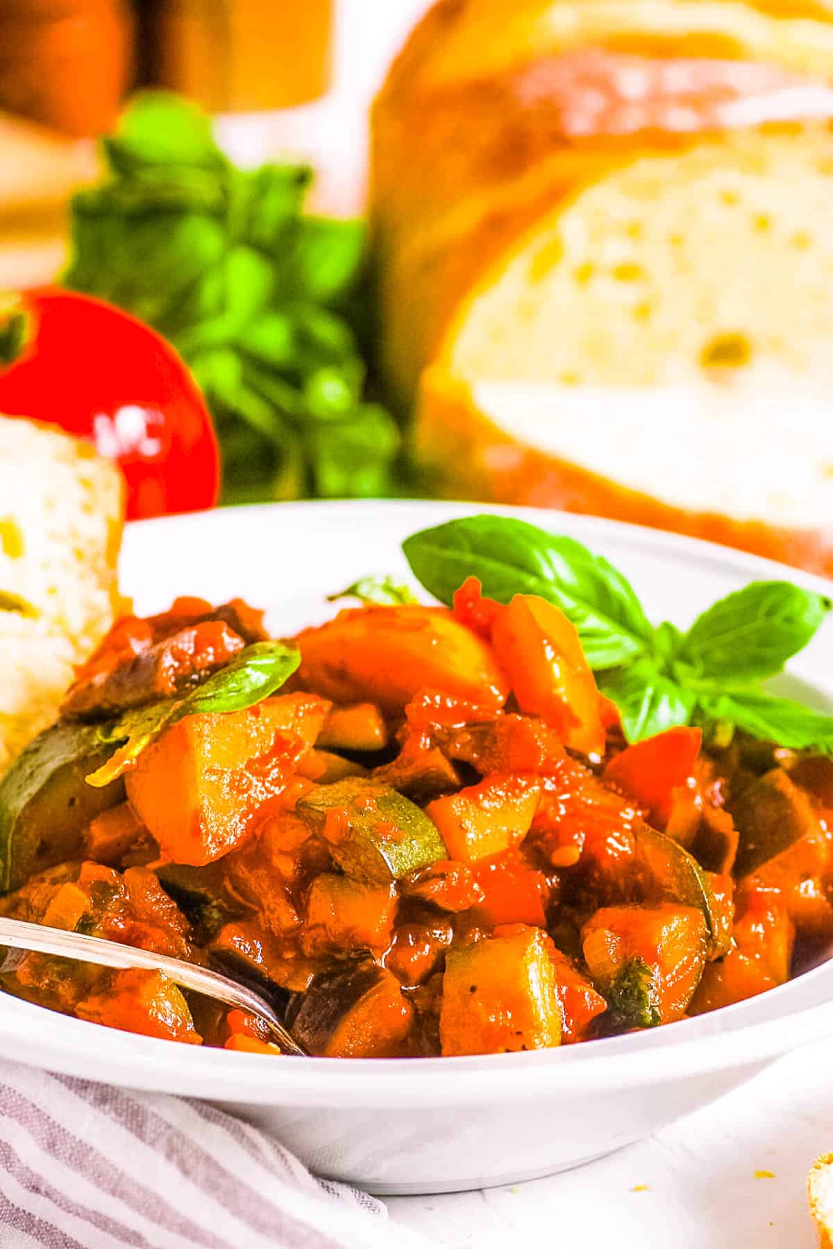 Healthy vegan Italian ratatouille with potatoes, also known as Ciambotta, served in a white bowl garnished with fresh basil.