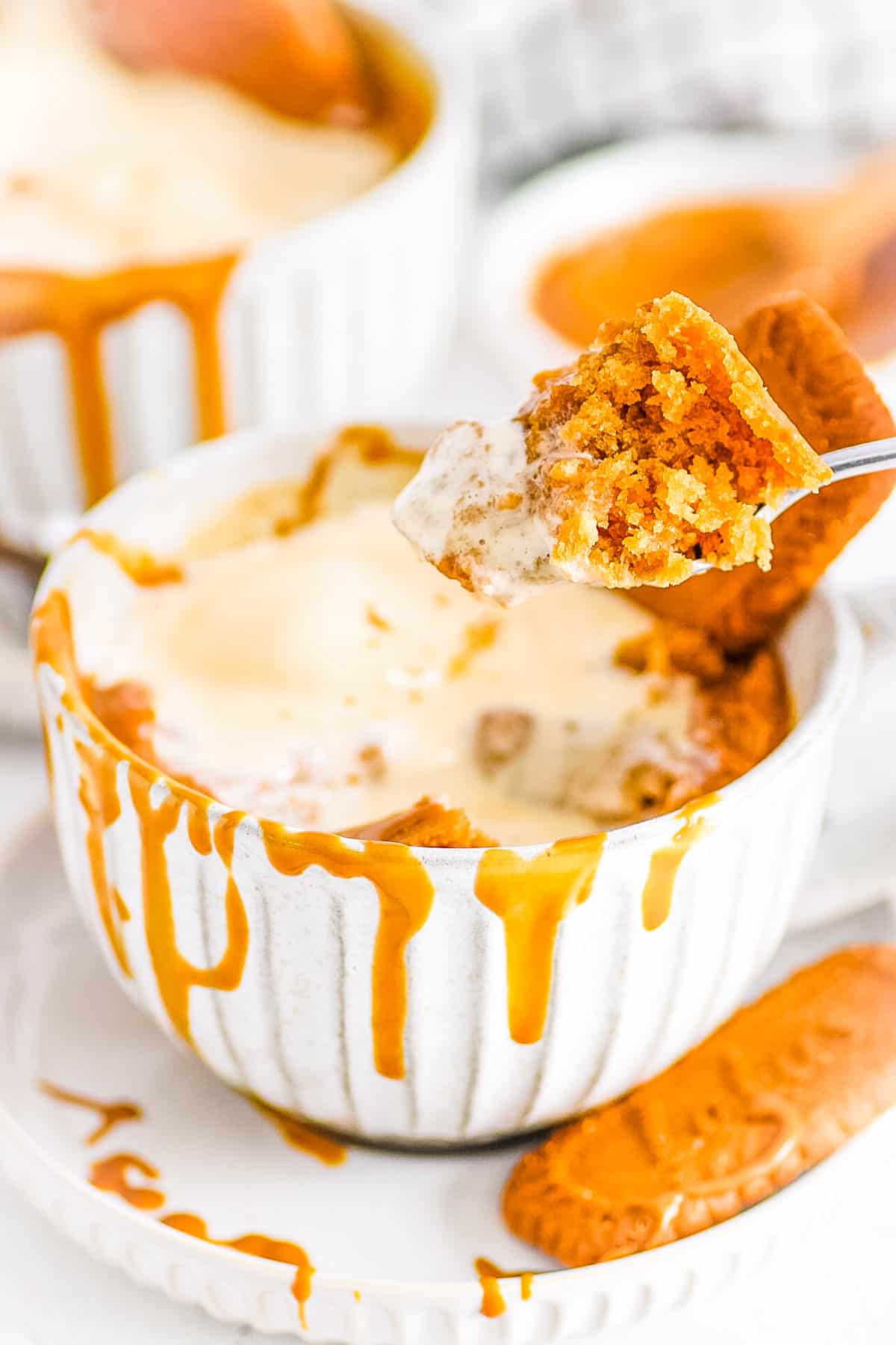 Bite taken out of vegan biscoff mug cake - served in a mug with ice cream and a drizzle of cookie butter.