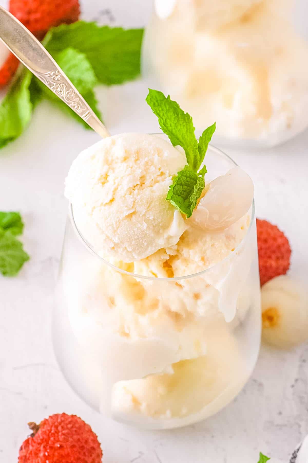 Creamy homemade lychee ice cream served in a glass with a mint garnish.