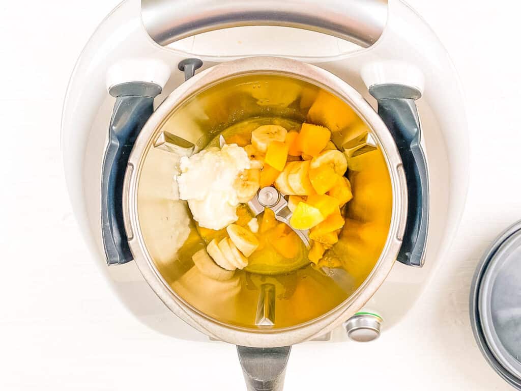 Mangoes, bananas, peaches, and yogurt in a blender.