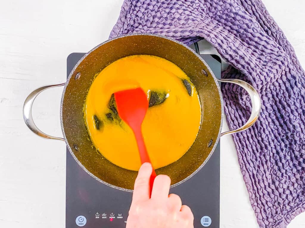 Homemade peach syrup cooking on the stove.