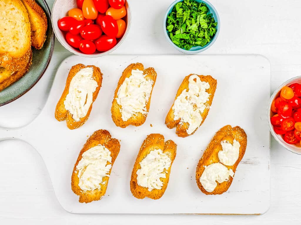 Burrata tomato toast on a white cutting board.