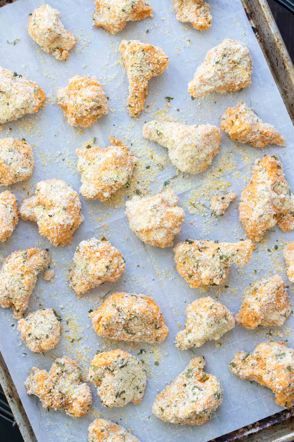 Breadcrumb coated cauliflower pieces on a baking sheet.