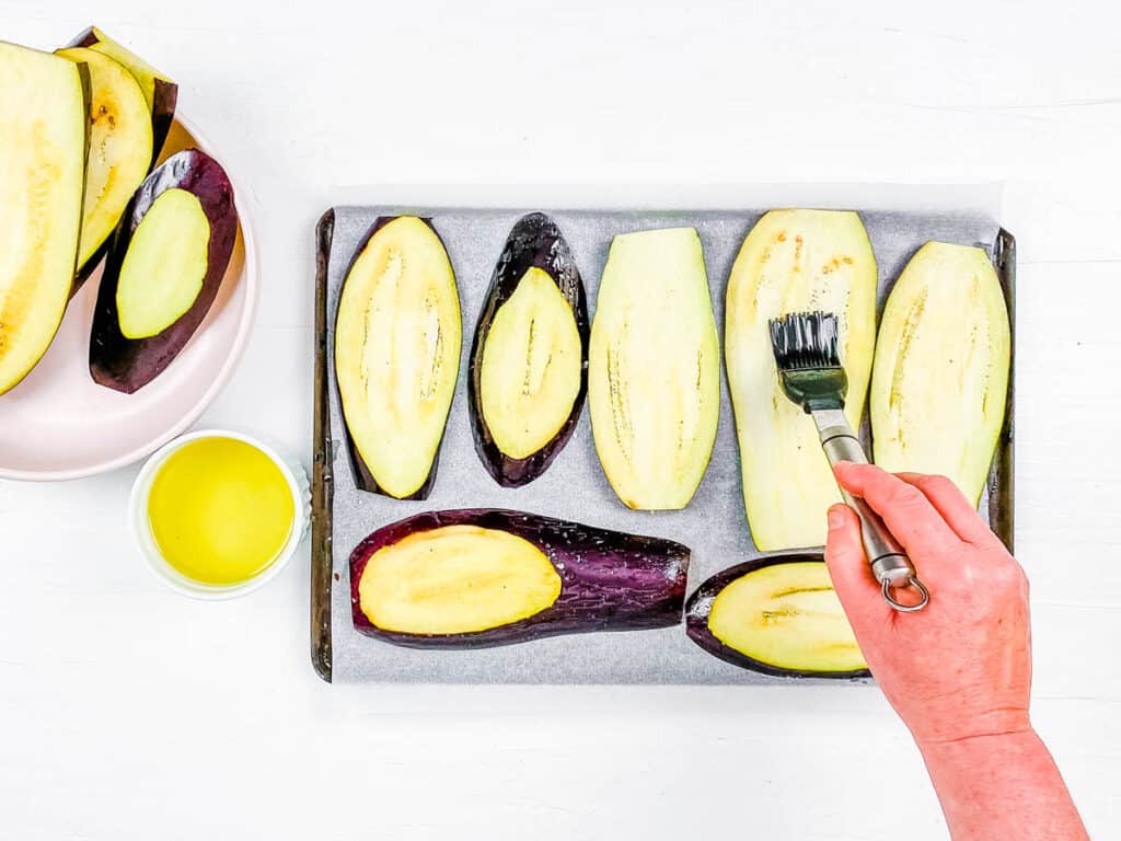 Eggplant slices brushed with olive oil on a baking sheet.