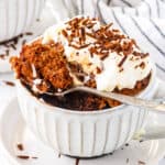 Chocolate protein mug cake served in a mug, topped with whipped cream and chocolate shavings.