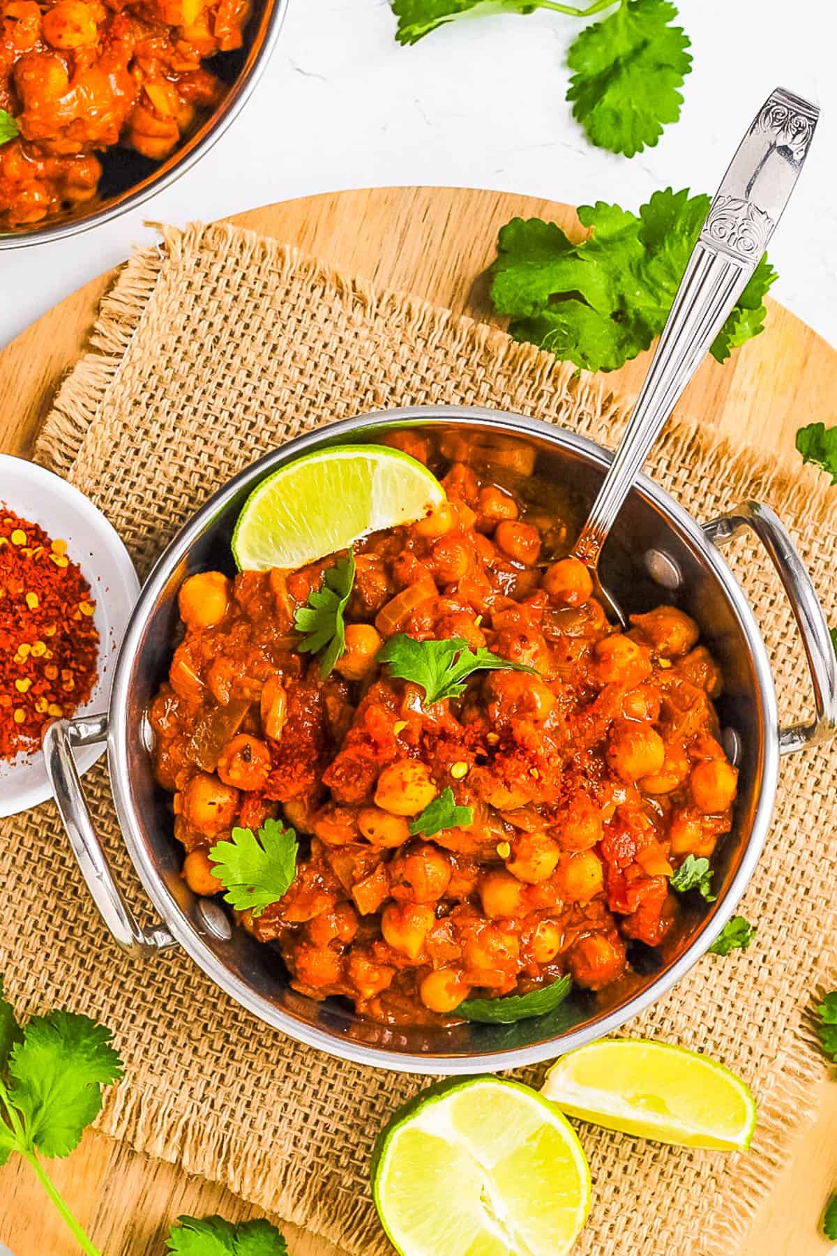 My chana masala served in a stainless steel bowl garnished with cilantro and lime.