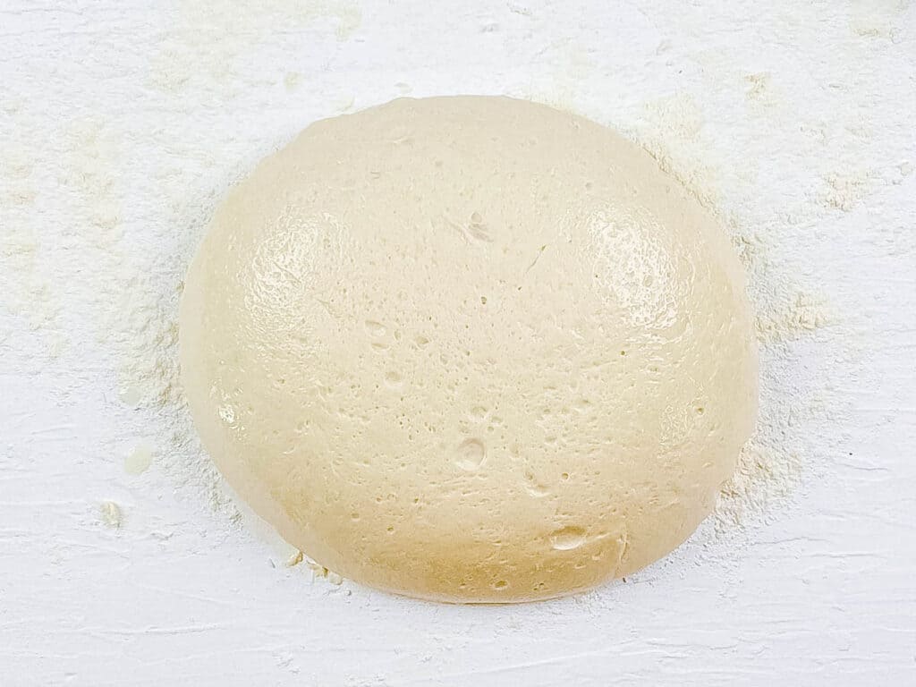 Poolish pizza dough ball on a cutting board.