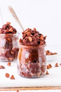 Easy edible brownie batter served in a glass jar, topped with chocolate chips.