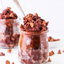 Easy edible brownie batter served in a glass jar, topped with chocolate chips.