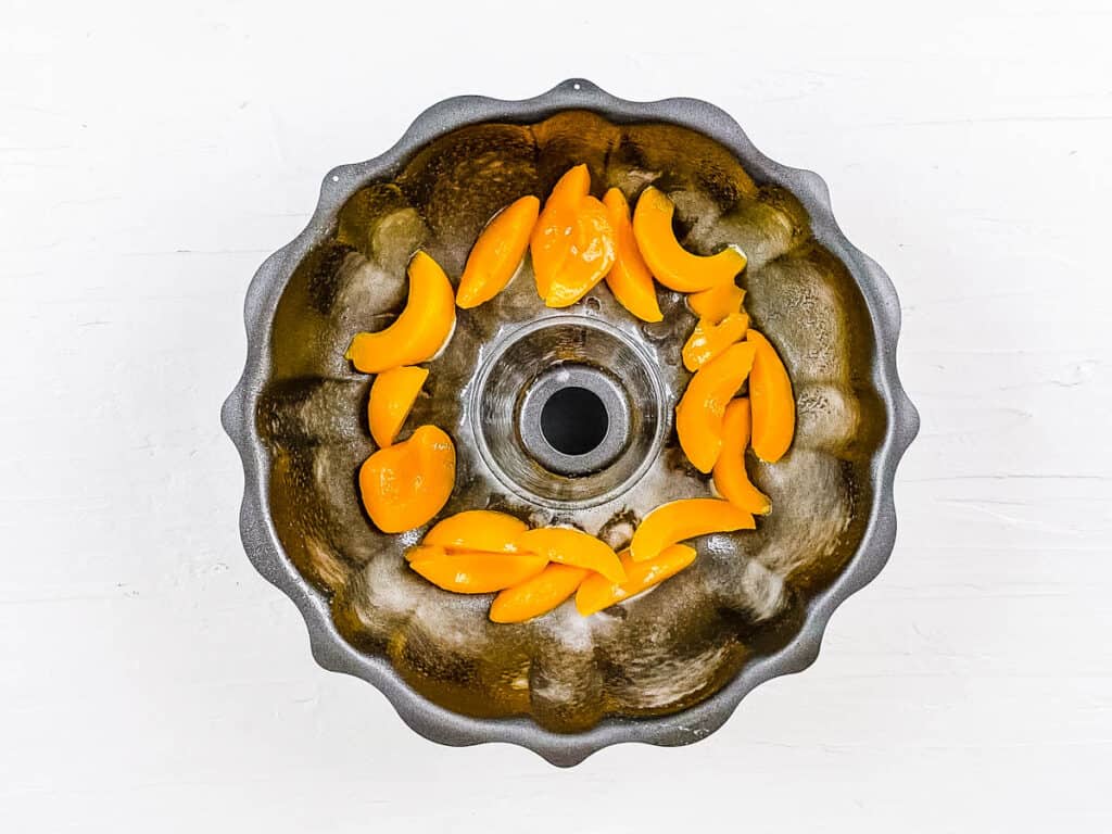 Peaches added to a bundt baking pan.