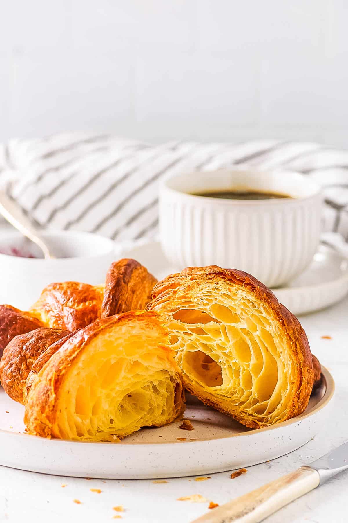 Homemade sourdough croissants, served on a white plate with coffee on the side.